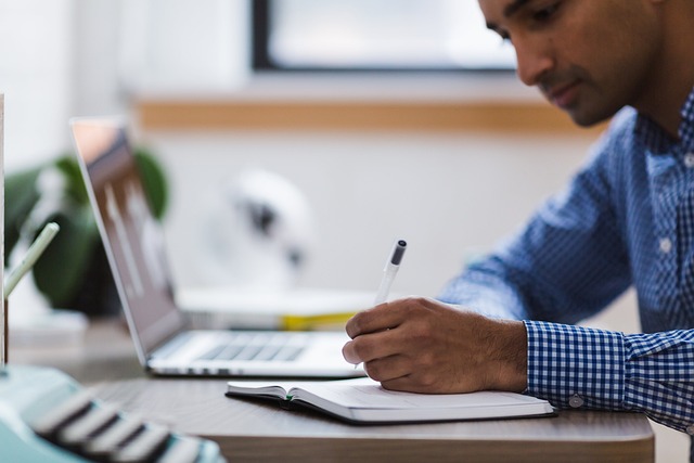 L’immagine mostra una persona seduta a una scrivania mentre prende appunti su un quaderno accanto a un computer portatile. La scena suggerisce un momento di studio, analisi e ricerca. L’immagine rappresenta il lavoro di approfondimento che sta alla base del progetto “Internazionale per la Pace”: la costruzione di percorsi culturali fondati su documentazione storica, studio delle fonti e riflessione critica.